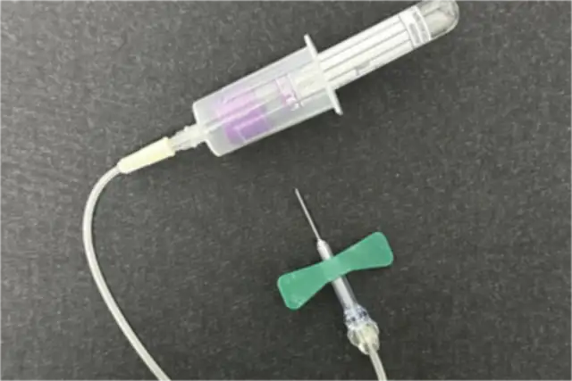 A butterfly needle set with its tubing and tube holder, next to a lavender-top tube